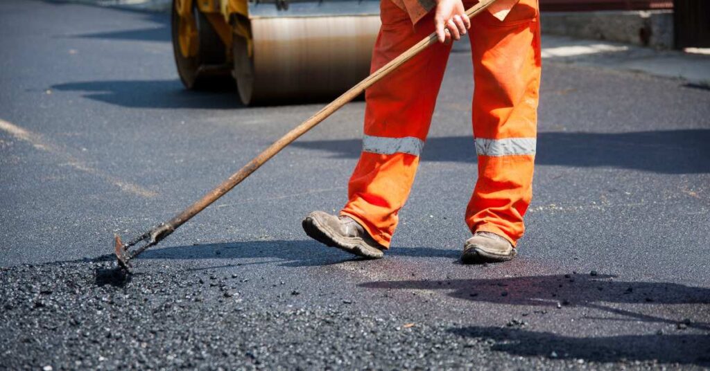Worker smoothing asphalt paving for a seamless and durable road surface during the paving process.