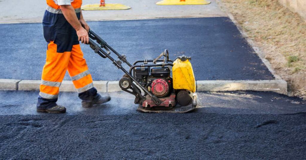 Asphalt paving worker operating a compactor on a newly laid road surface for smooth and durable finish.