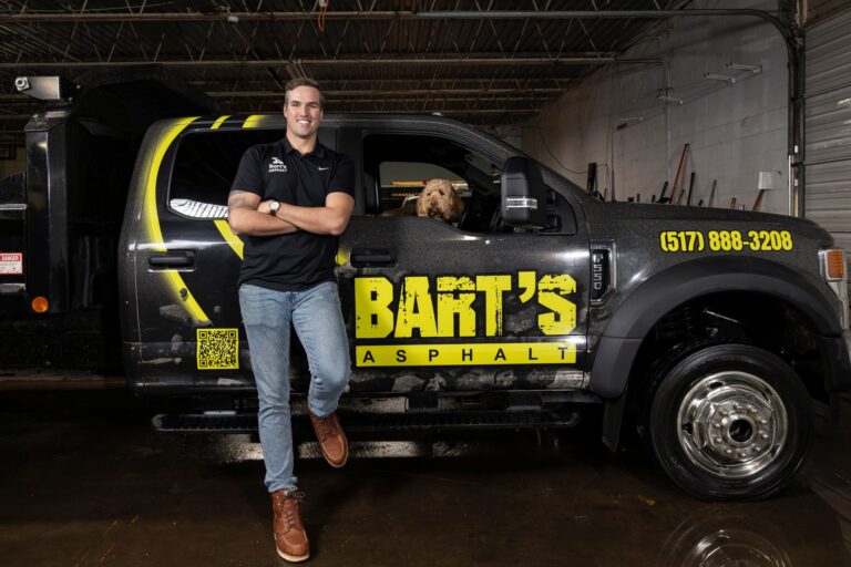 a man leaning on a truck with a dog in the window