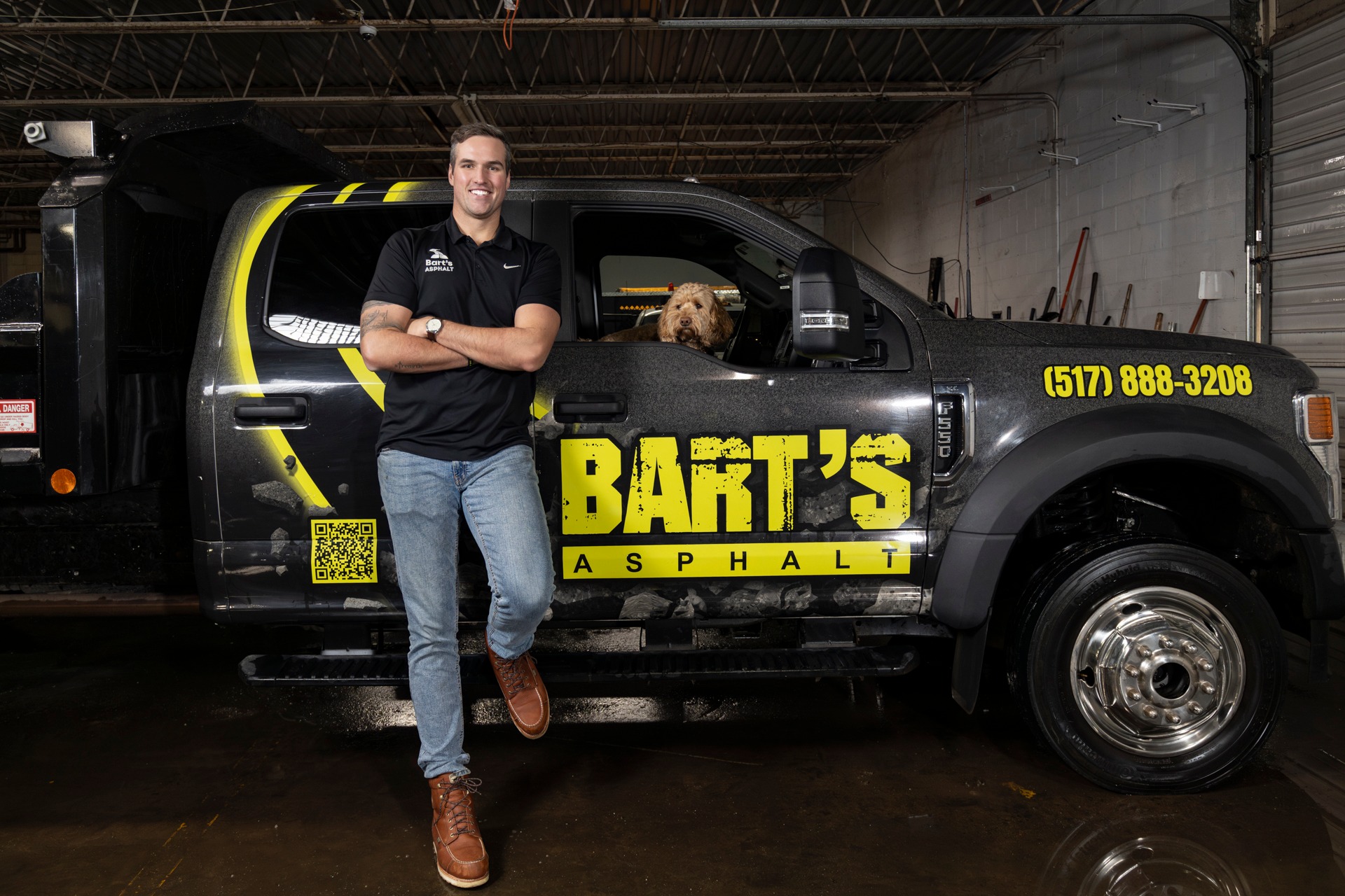 a man leaning on a truck with a dog in the window
